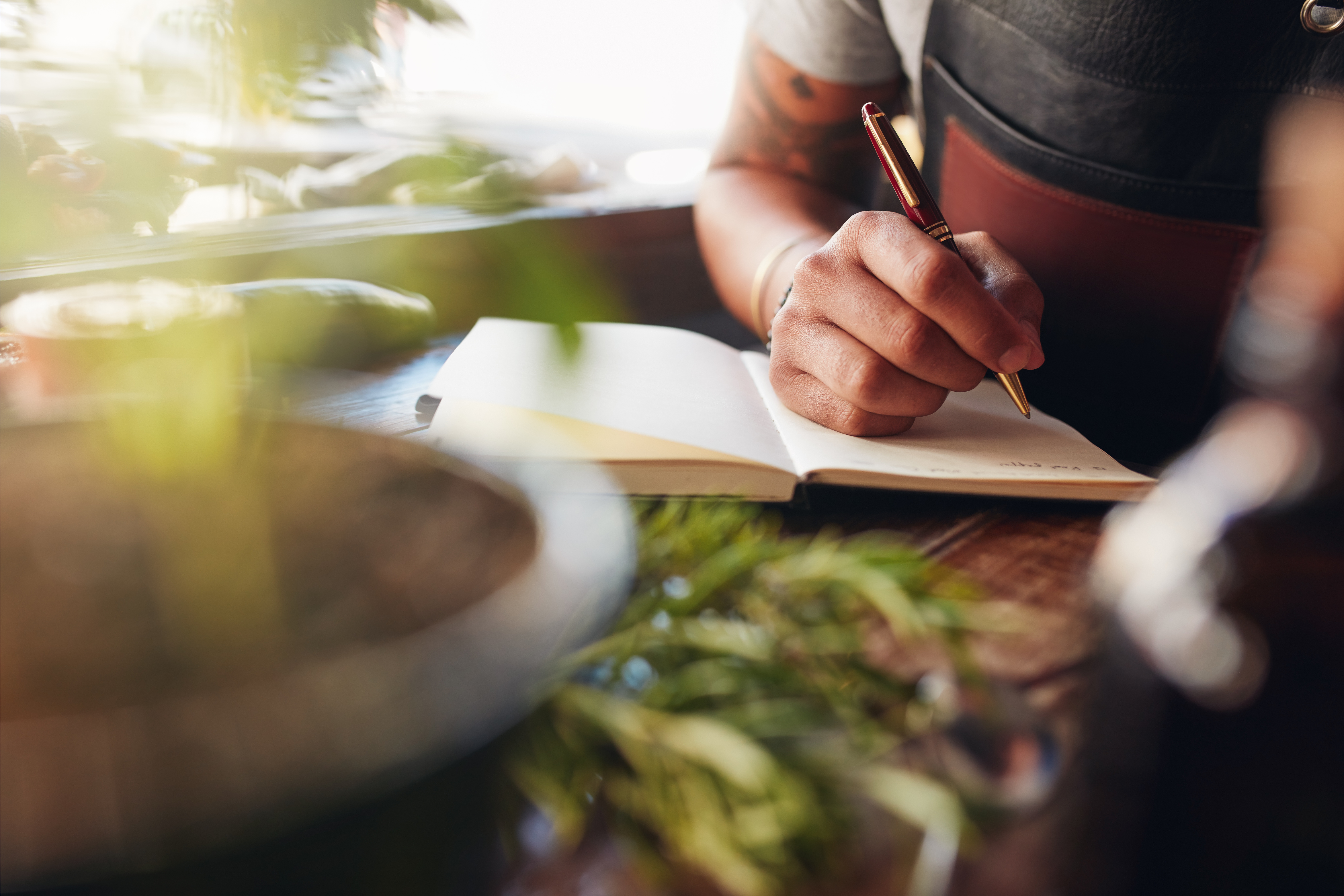 Pflanzen, Buch und Hand mit Kugelschreiber